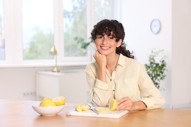 Woman with cut lemons at table indoors