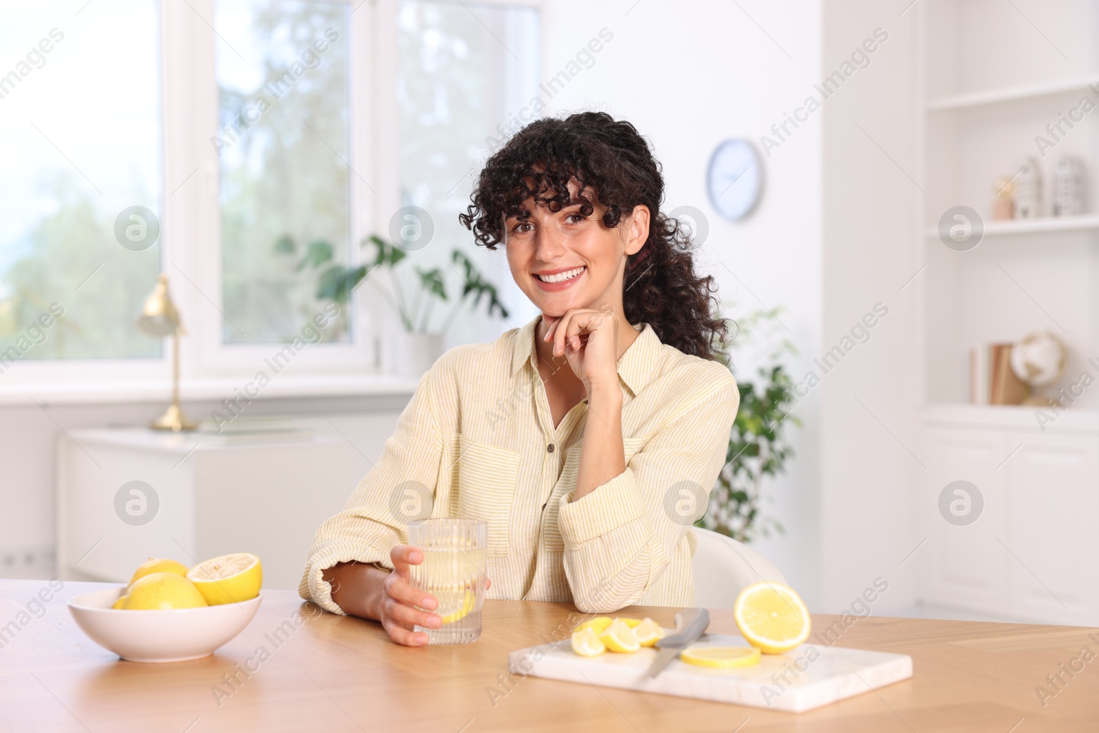 Photo of Woman with glass of lemon water indoors