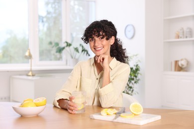 Woman with glass of lemon water indoors