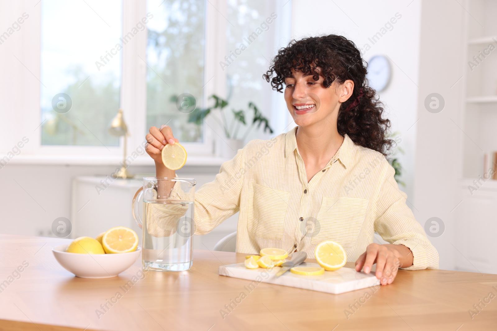 Photo of Woman making lemon water at table indoors