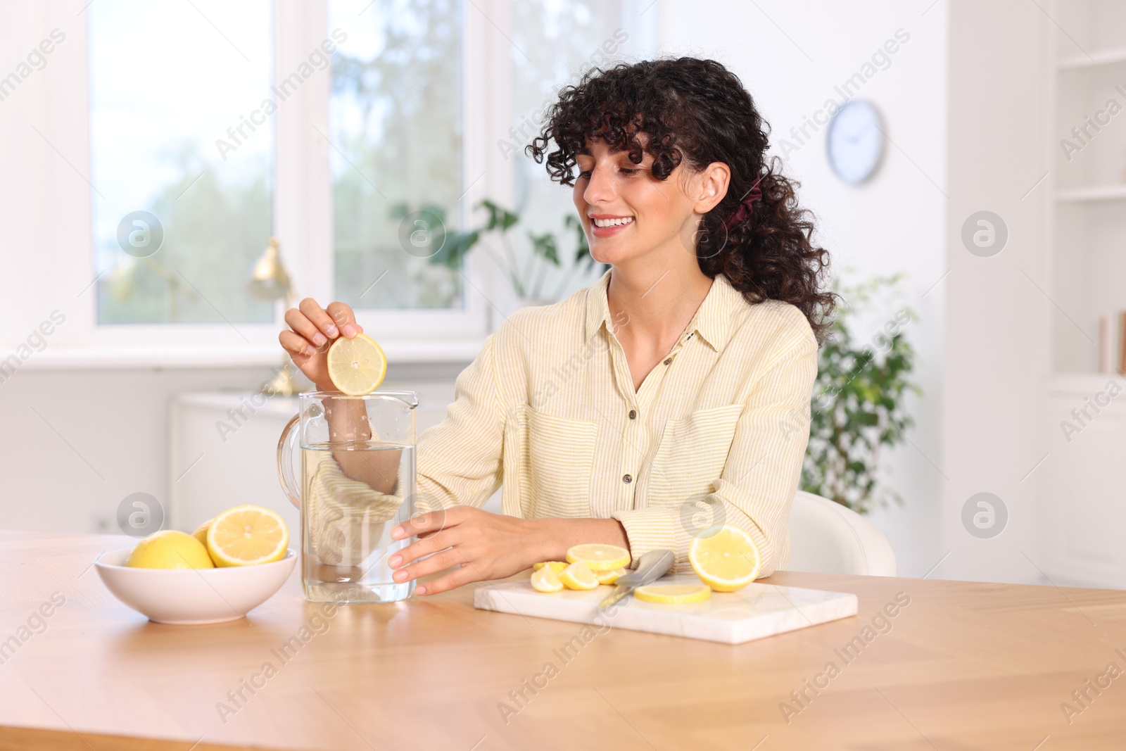 Photo of Woman making lemon water at table indoors