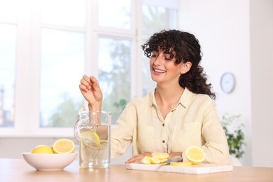 Photo of Woman making lemon water at table indoors