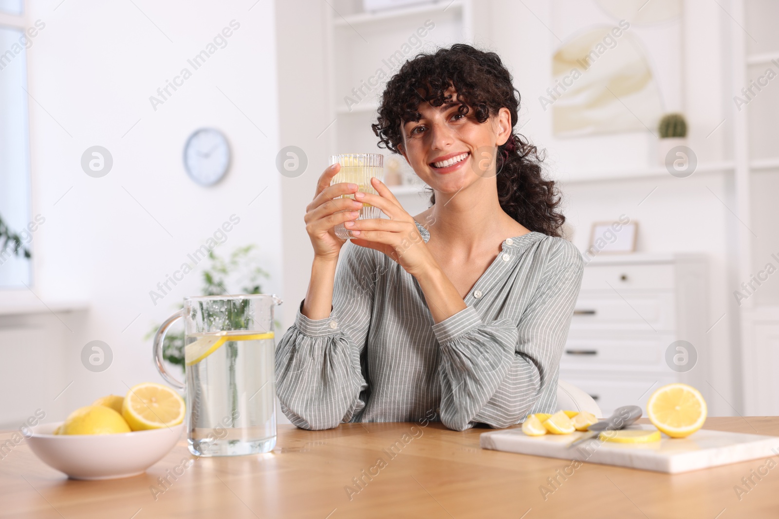 Photo of Woman with glass of lemon water indoors