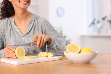 Making lemon water. Woman cutting fruit at wooden table indoors, closeup