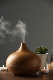 Aroma oil diffuser, houseplants and burning candles on wooden table