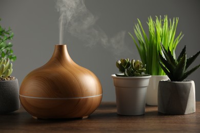 Aroma oil diffuser and houseplants on wooden table