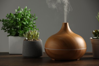 Aroma oil diffuser and houseplants on wooden table