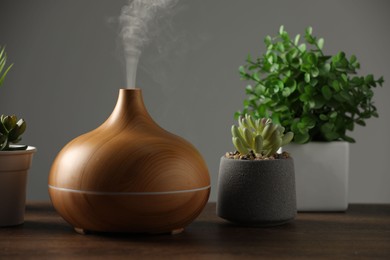 Aroma oil diffuser and houseplants on wooden table