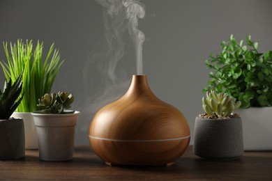 Aroma oil diffuser and houseplants on wooden table