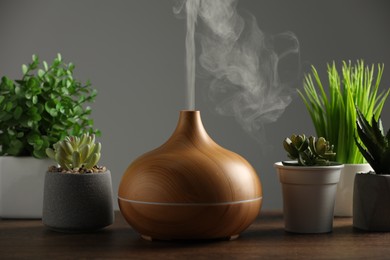 Aroma oil diffuser and houseplants on wooden table