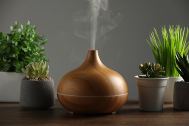 Aroma oil diffuser and houseplants on wooden table