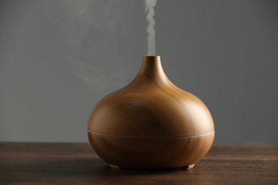 Aroma oil diffuser with steam on wooden table