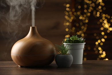 Aroma oil diffuser and houseplants on wooden table