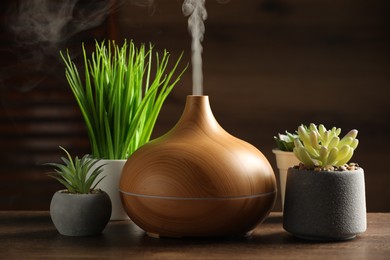 Aroma oil diffuser and houseplants on wooden table