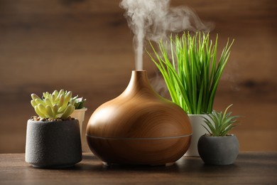 Aroma oil diffuser and houseplants on wooden table