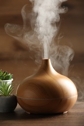 Aroma oil diffuser and houseplants on wooden table