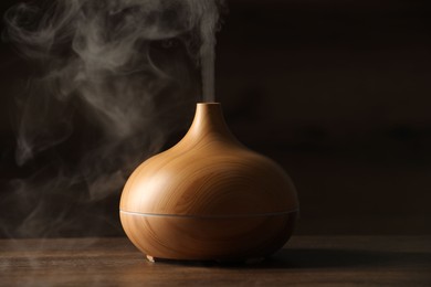 Photo of Aroma oil diffuser with steam on wooden table