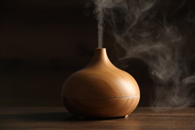 Photo of Aroma oil diffuser with steam on wooden table