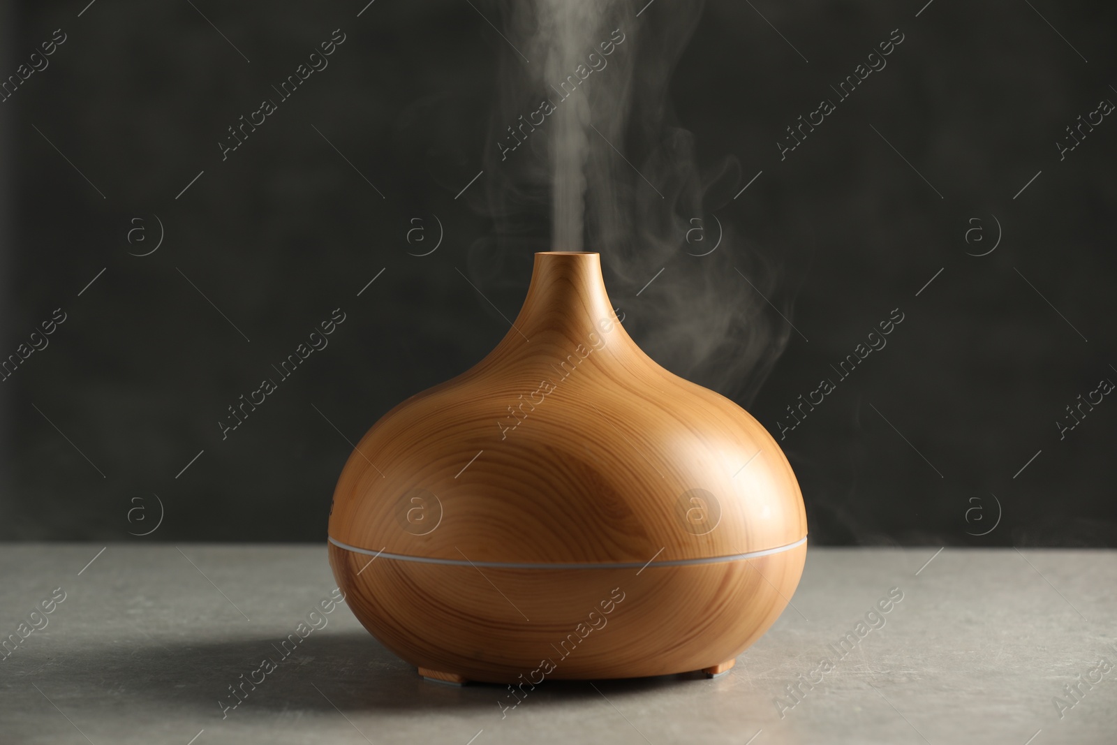 Photo of Aroma oil diffuser with steam on light grey table