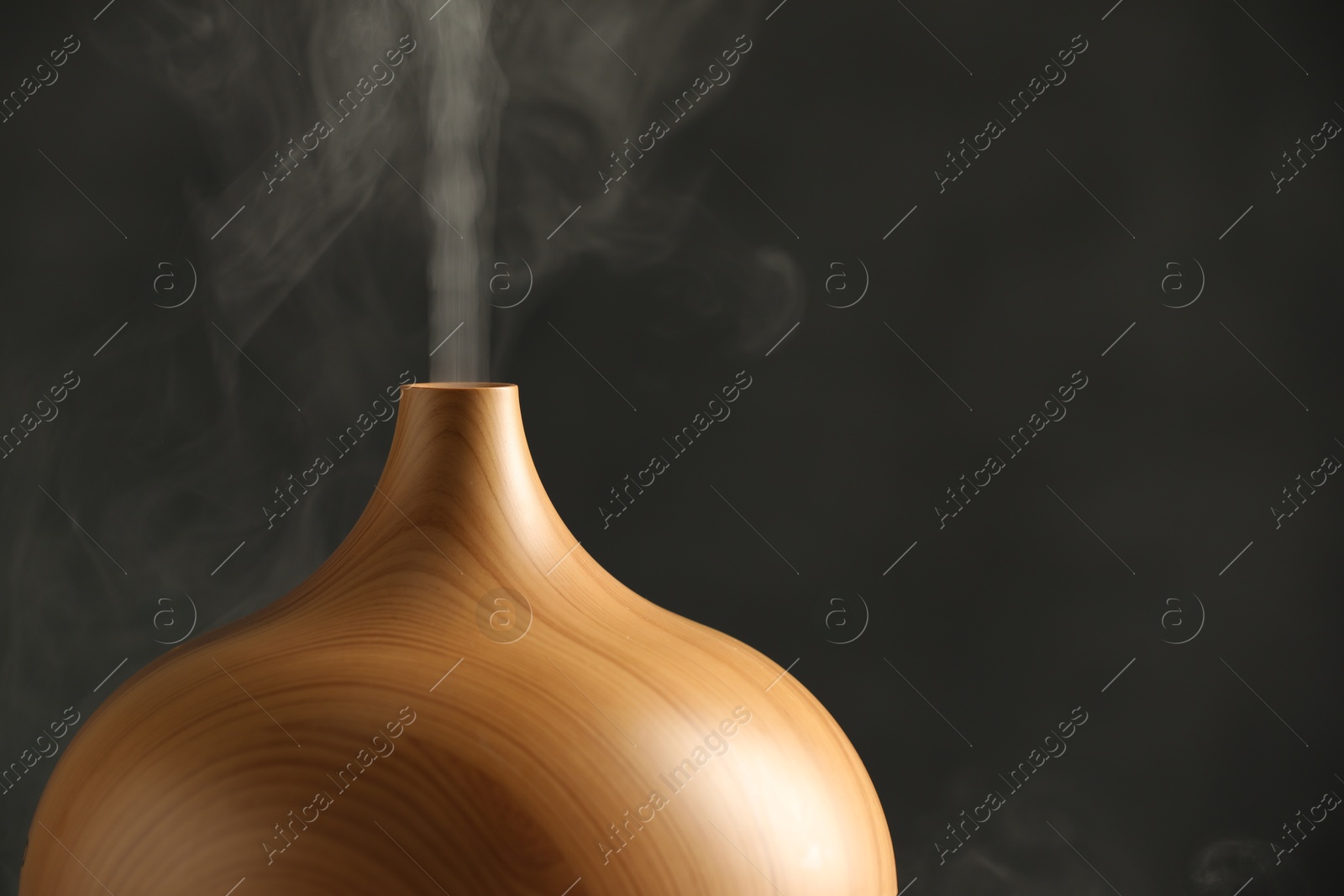 Photo of Aroma oil diffuser with steam on grey background, closeup. Space for text