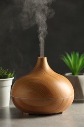 Photo of Aroma oil diffuser and houseplants on light grey table