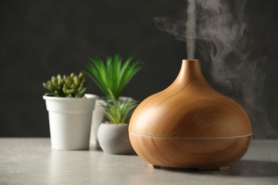 Aroma oil diffuser and houseplants on light grey table