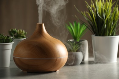 Aroma oil diffuser and houseplants on light grey table