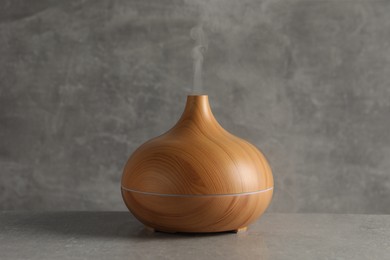 Photo of Aroma oil diffuser with steam on light grey table