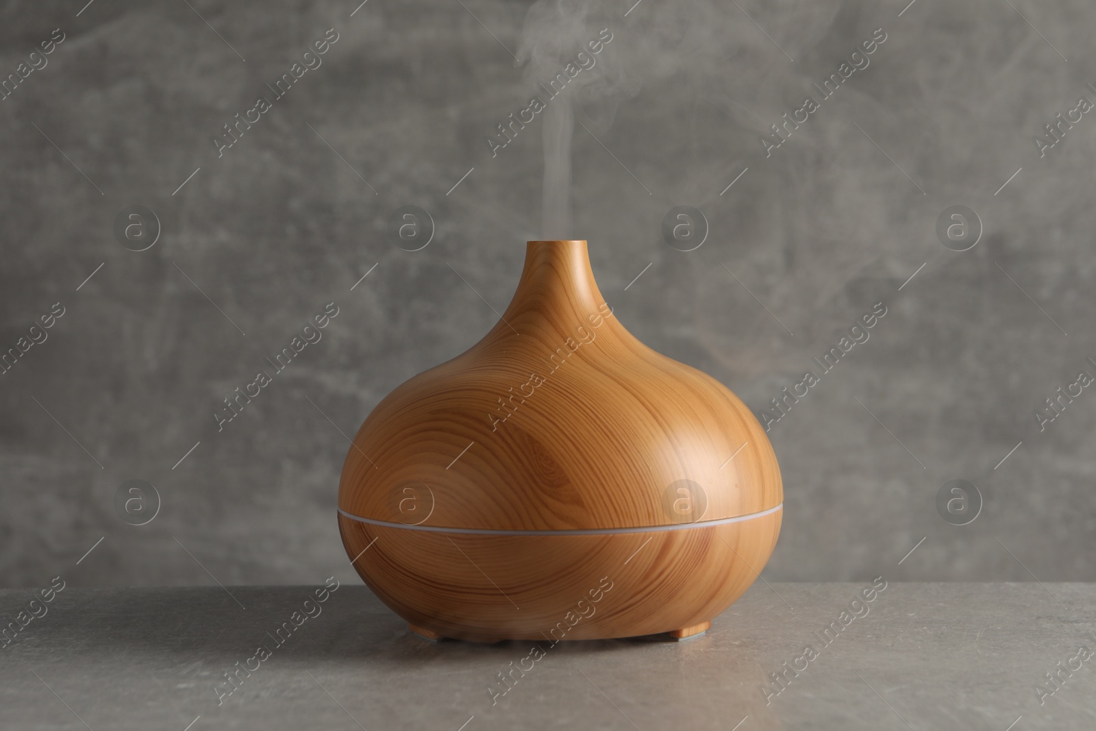 Photo of Aroma oil diffuser with steam on light grey table