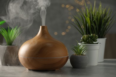 Aroma oil diffuser and houseplants on light grey table