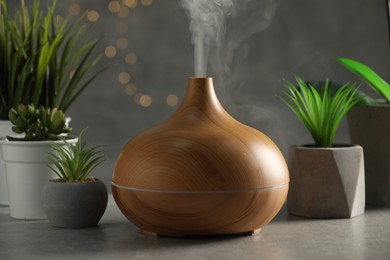 Aroma oil diffuser and houseplants on light grey table