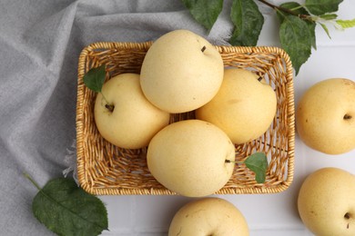 Photo of Delicious fresh apple pears and green leaves on white table, top view