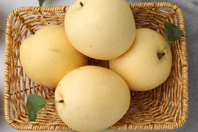 Photo of Delicious fresh apple pears in wicker basket on table, top view