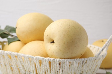 Photo of Delicious fresh apple pears in wicker basket on table, closeup