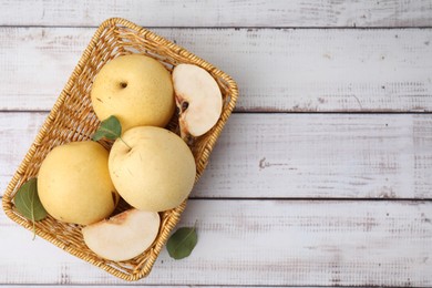 Delicious fresh apple pears in basket on white wooden table, top view. Space for text