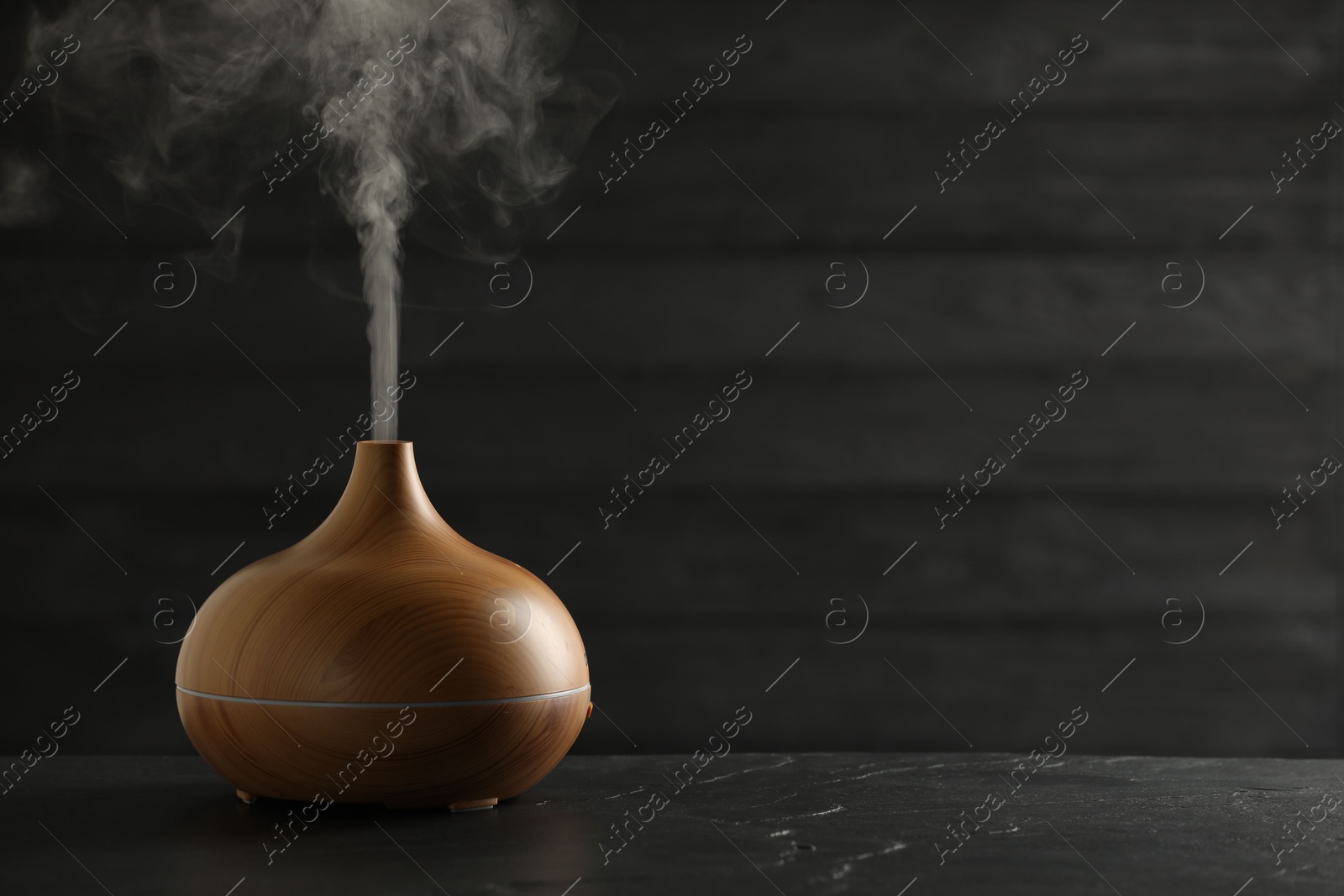 Photo of Aroma oil diffuser on black table, space for text