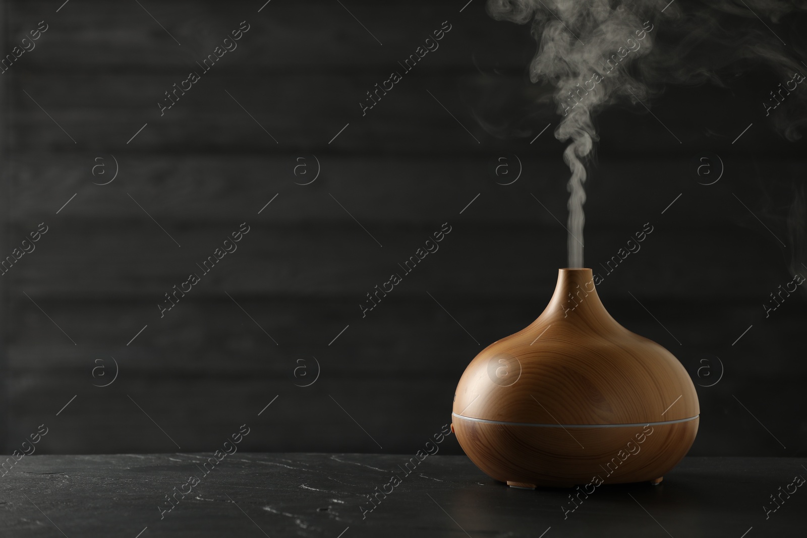 Photo of Aroma oil diffuser on black table, space for text