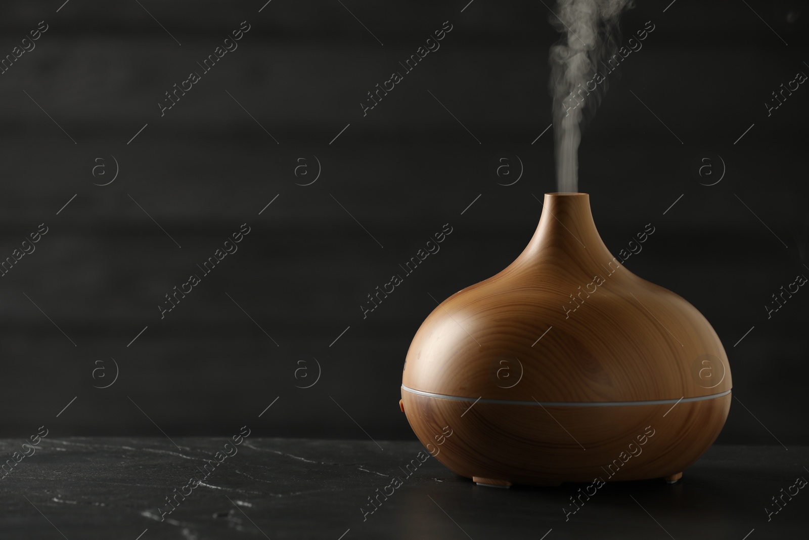 Photo of Aroma oil diffuser on black table, space for text