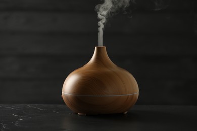 Aroma oil diffuser with steam on black table