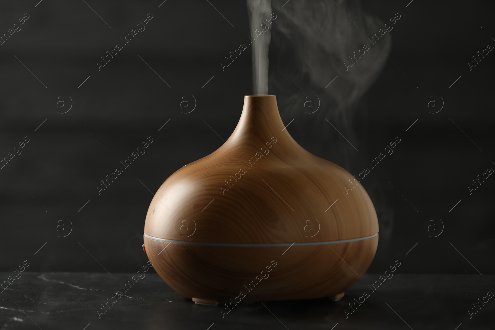 Photo of Aroma oil diffuser with steam on black table