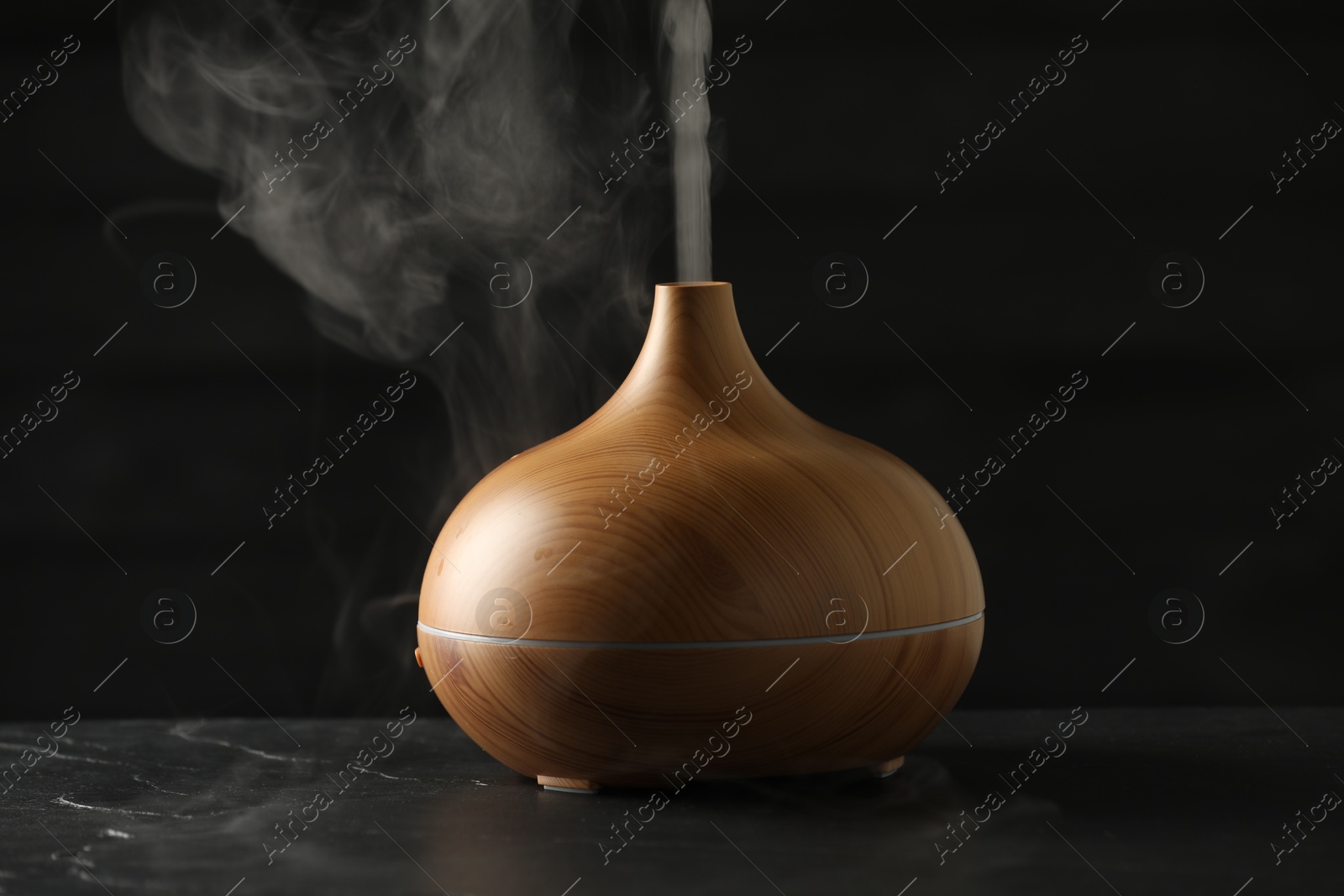 Photo of Aroma oil diffuser with steam on black table