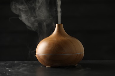 Aroma oil diffuser with steam on black table