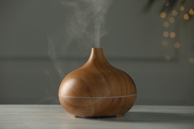 Photo of Aroma oil diffuser on white wooden table