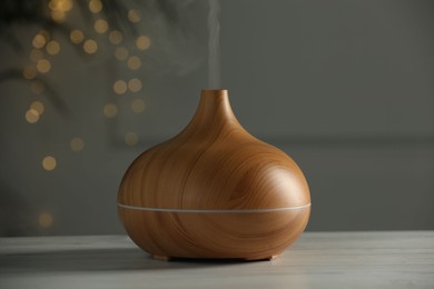 Photo of Aroma oil diffuser on white wooden table