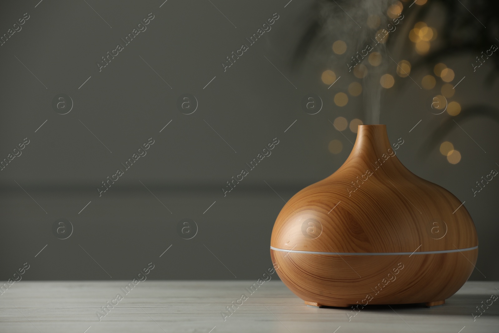 Photo of Aroma oil diffuser on white wooden table, space for text