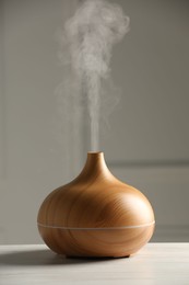 Photo of Aroma oil diffuser on white wooden table