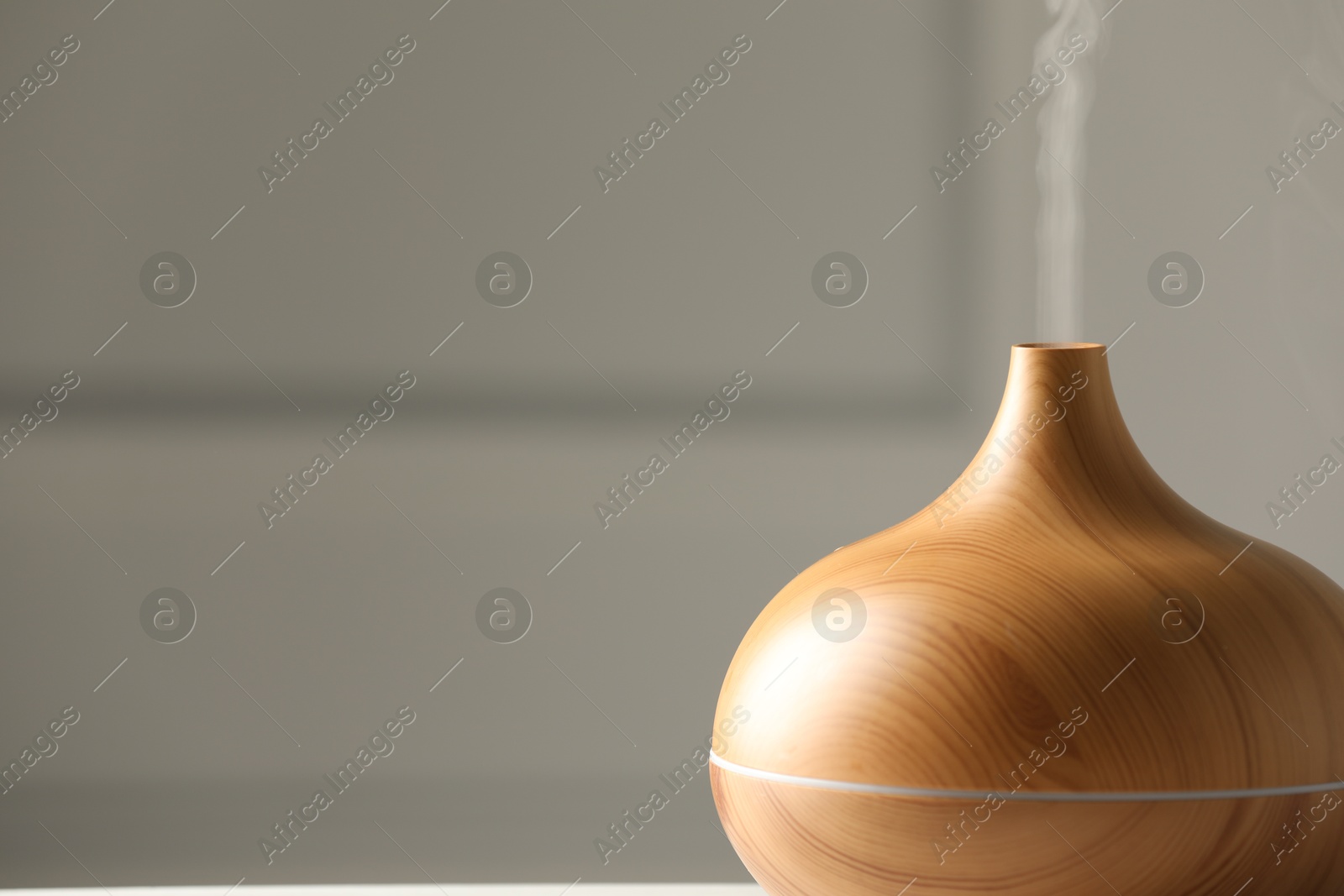 Photo of Aroma oil diffuser on grey background, closeup. Space for text