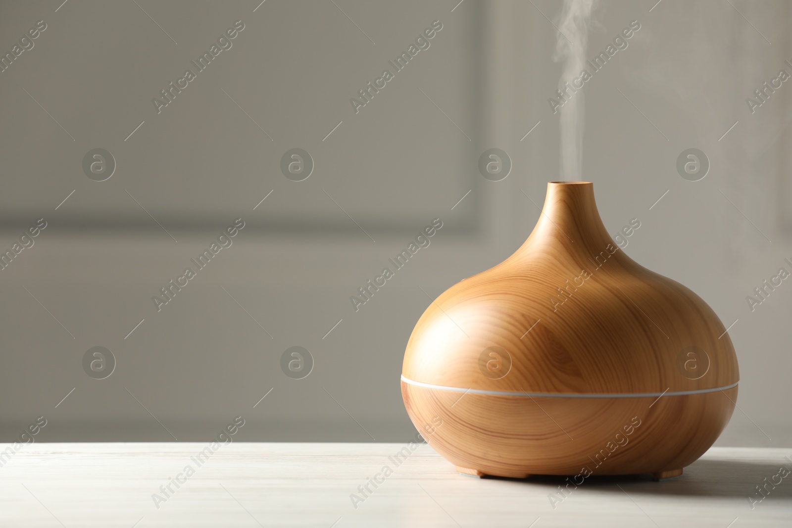 Photo of Aroma oil diffuser on white wooden table, space for text