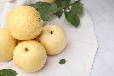 Photo of Delicious fresh apple pears and green leaves on white tiled table, closeup. Space for text