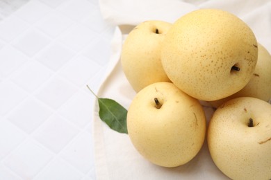 Photo of Delicious fresh apple pears and green leaf on white tiled table, closeup. Space for text